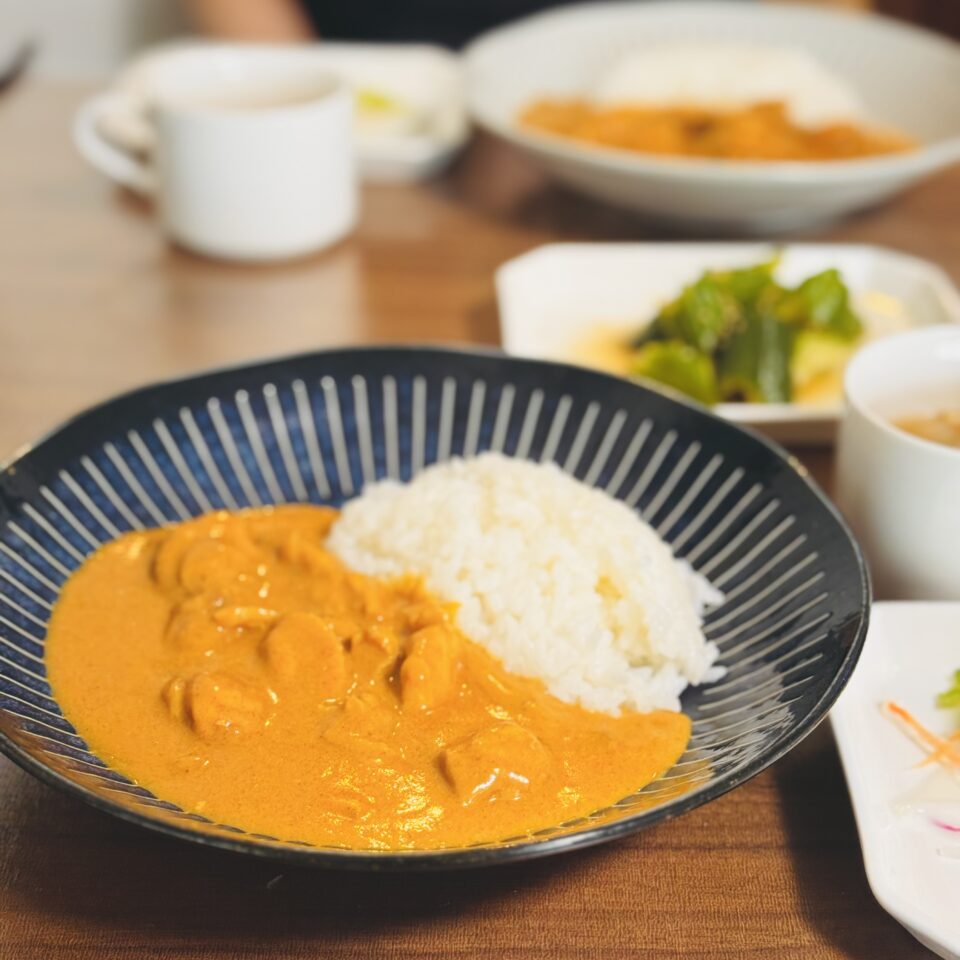 バターチキンカレーとサラダが机に置かれている